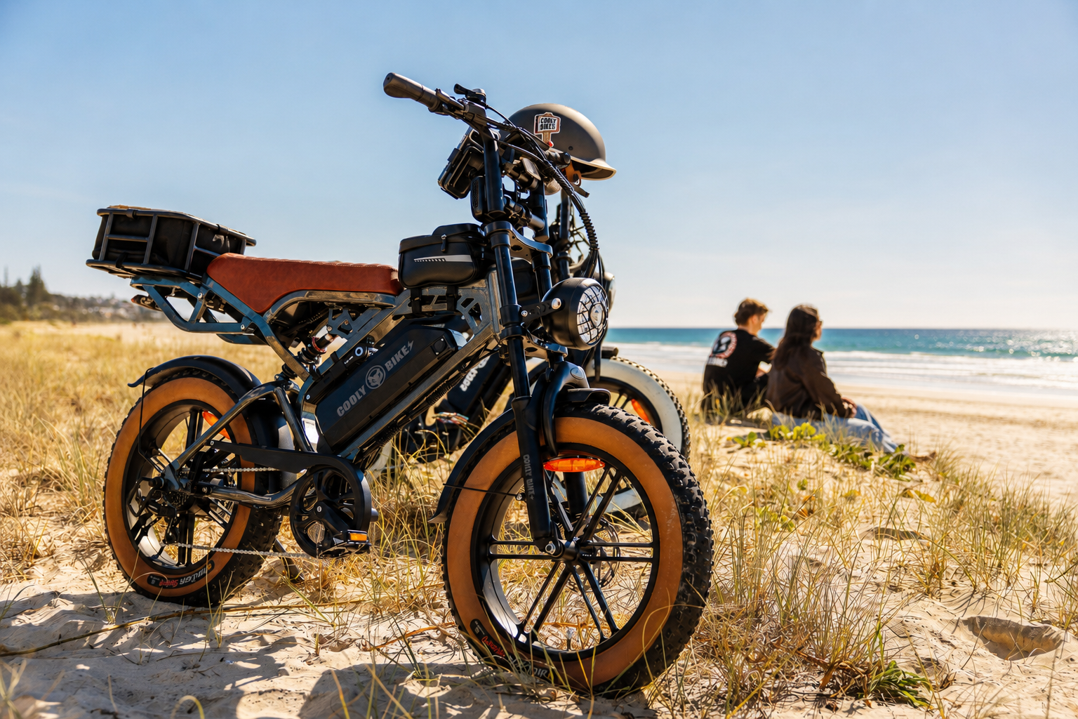 **Alt text:** Cooly fat tyre electric bike with helmet, rear rack and riding accessories parked beside an Australian beach.